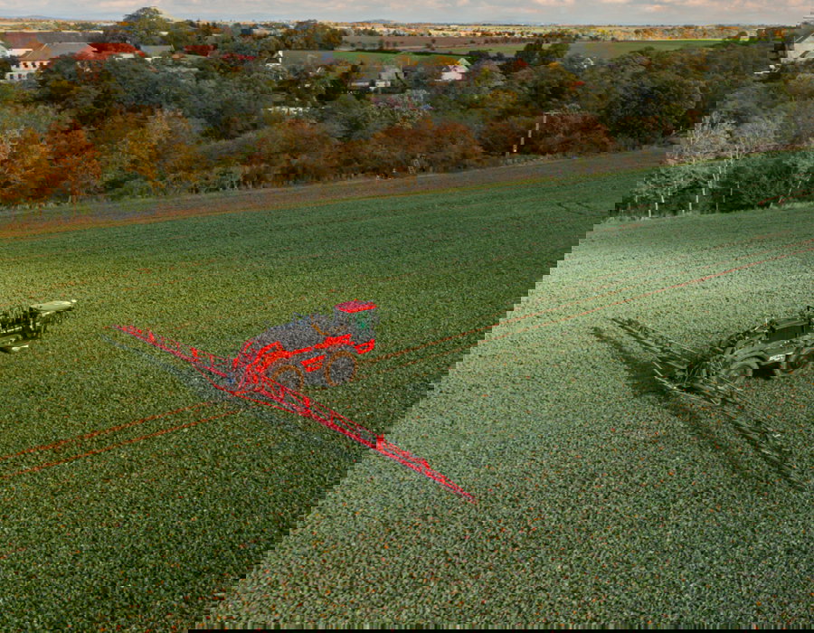 Aerial view of an Agrifac sprayer driving in a vast agricultural field, showcasing modern farming techniques.