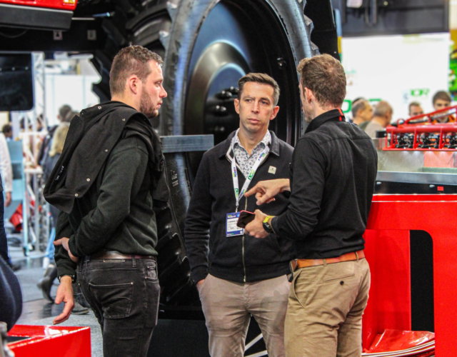Three people talking during an indoor event.