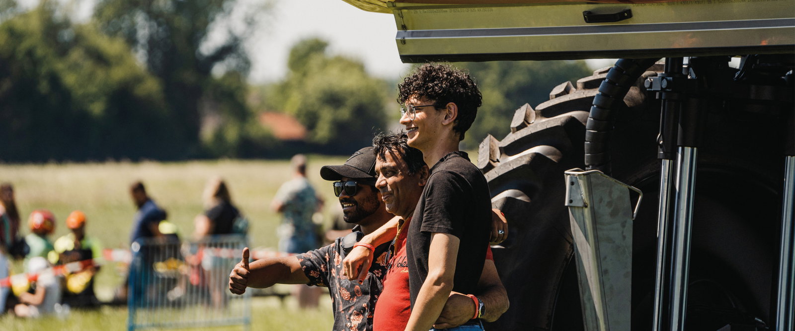 Three people looking happy behind a sprayer at an event.