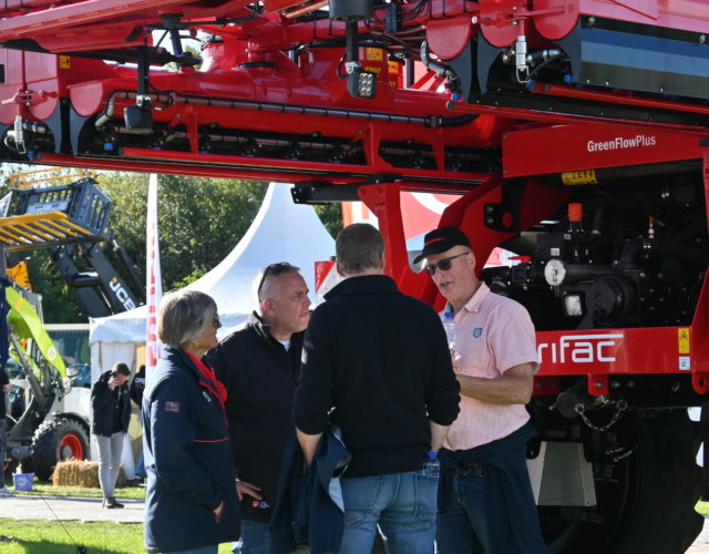 A group of people standing next to a machine at an outdoor exhibition.