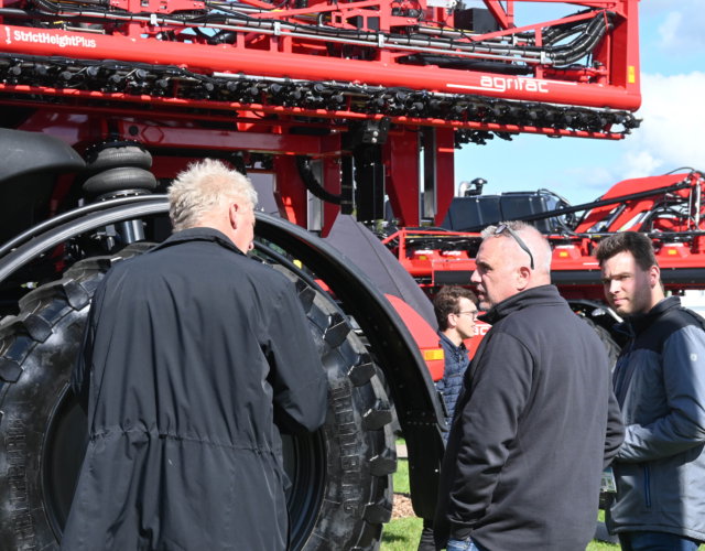 Three people in conversation in front of a sprayer.