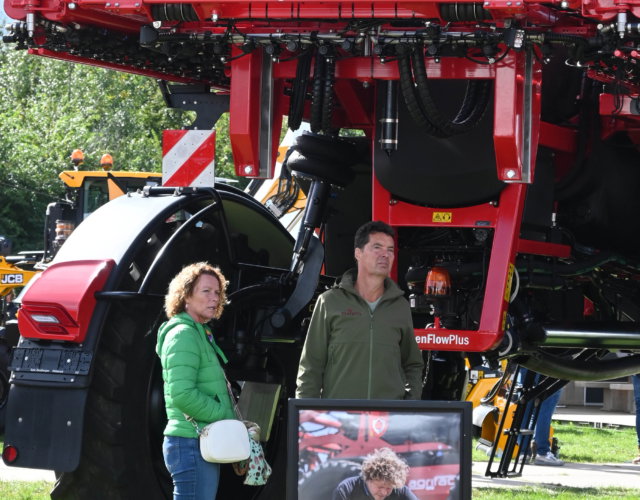 Two people standing next to a machine at an outdoor exhibition.