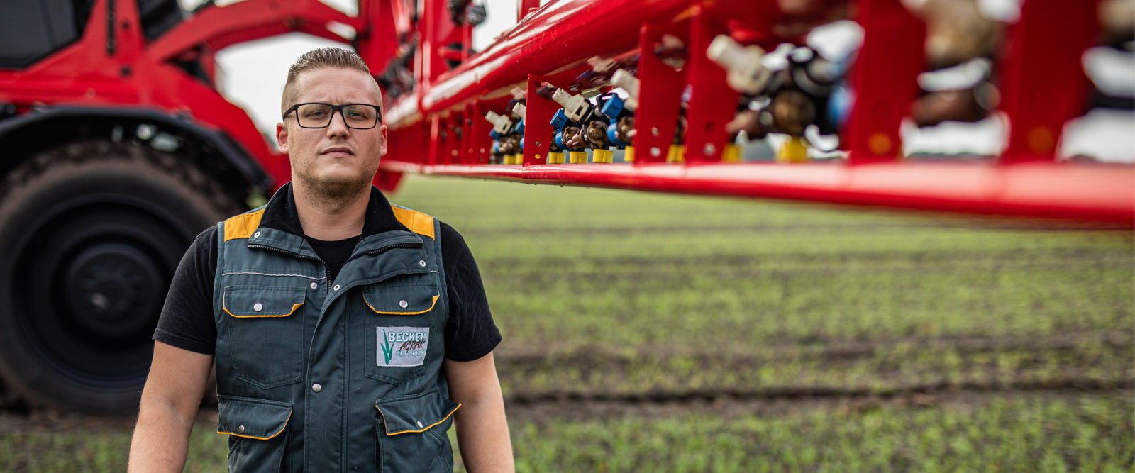 A man standing right in front of an Agrifac sprayer.