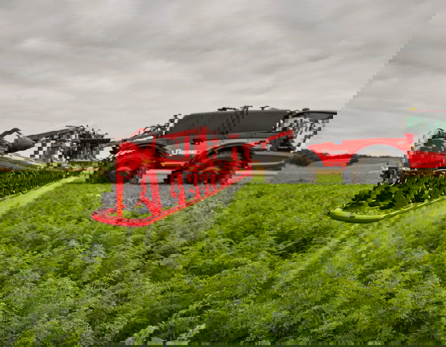 Side view of the machine with the J-boom spraying crops.