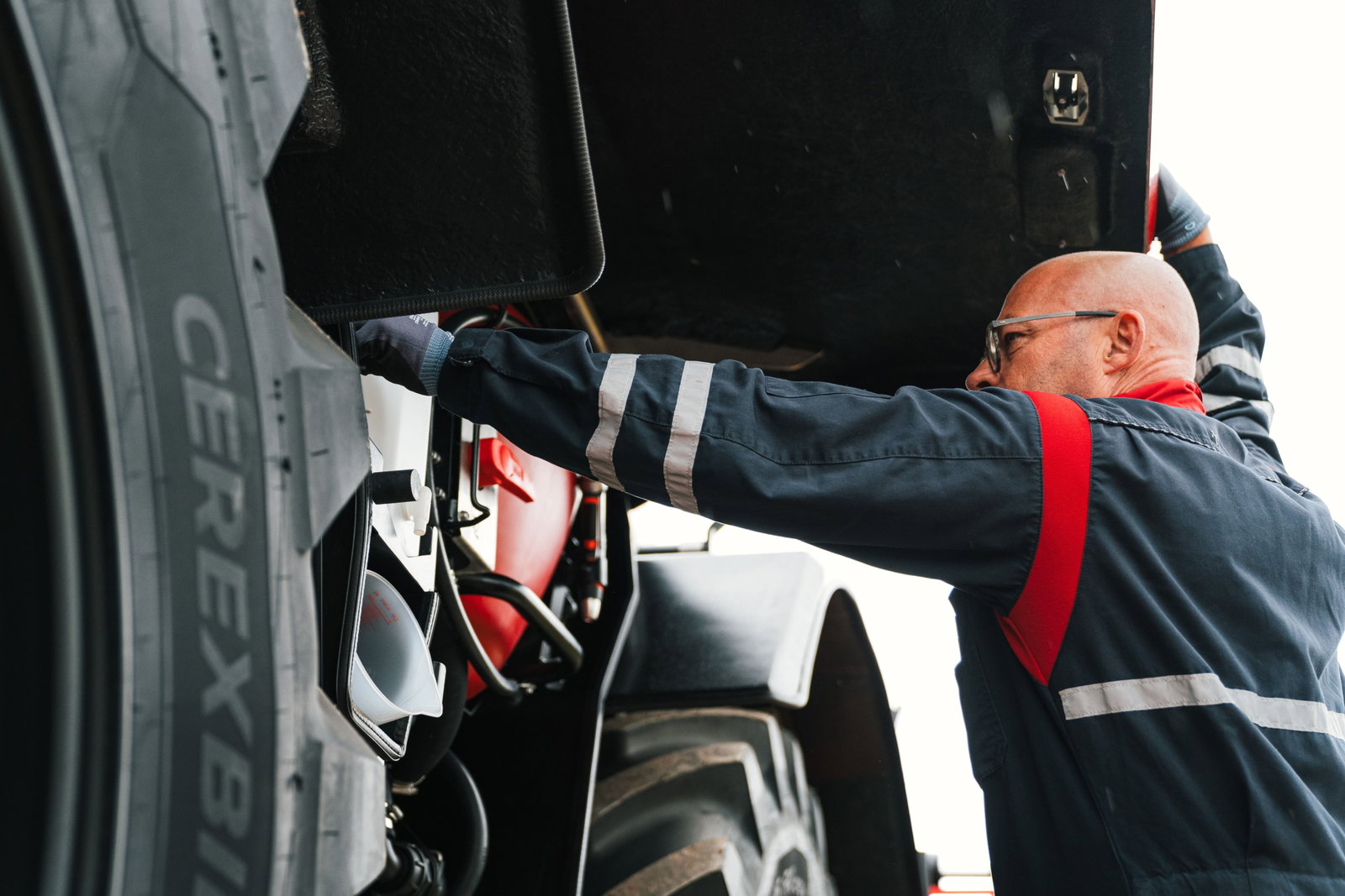 A man wearing a blue and red is working on an Agrifac sprayer.