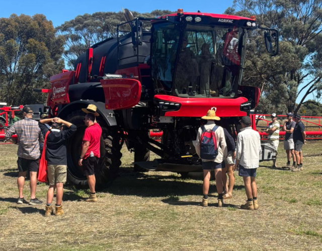 People gathering around an Argrifac sprayer during an event.