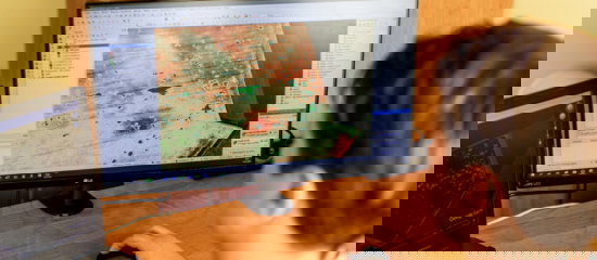 A man sits at a desk, focused on a computer screen displaying a detailed task map for navigation or planning purposes.