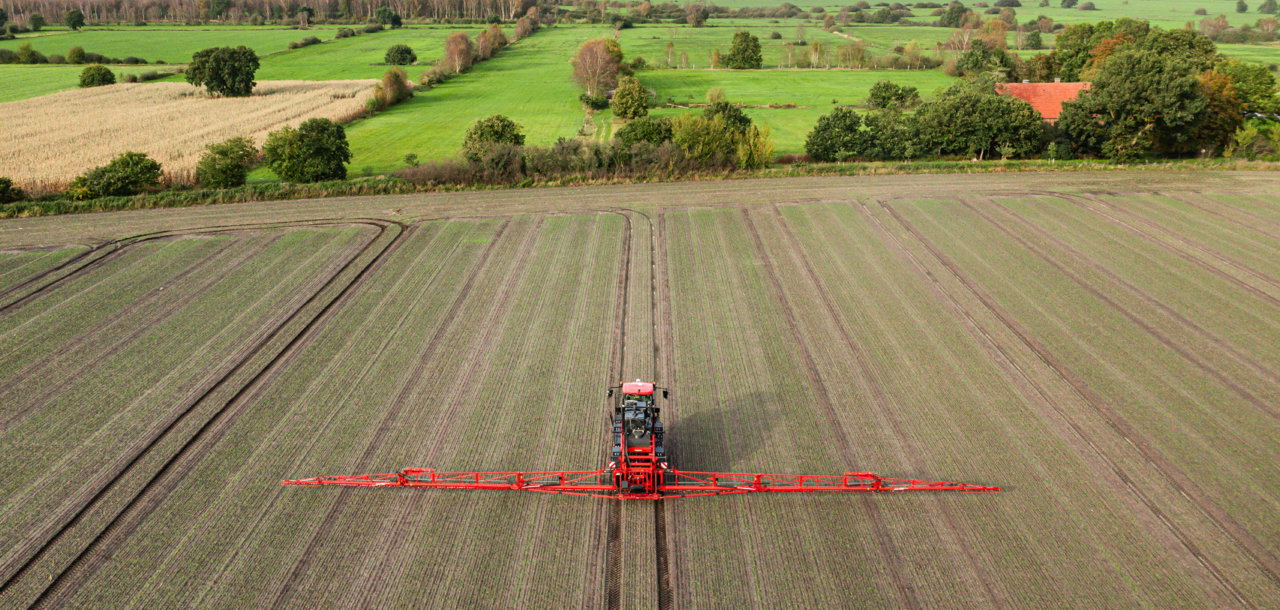 Aerial view of an Agrifac Condor sprayer driving through a large agricultural field.