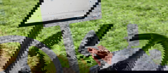 A close up view of the inside of the Agrifac cab with different buttons and a screen.