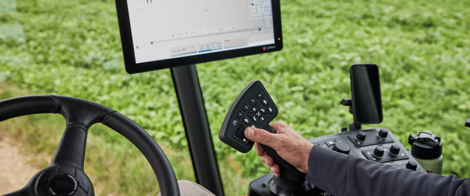 A close up view of the inside of the Agrifac cab with different buttons and a screen.