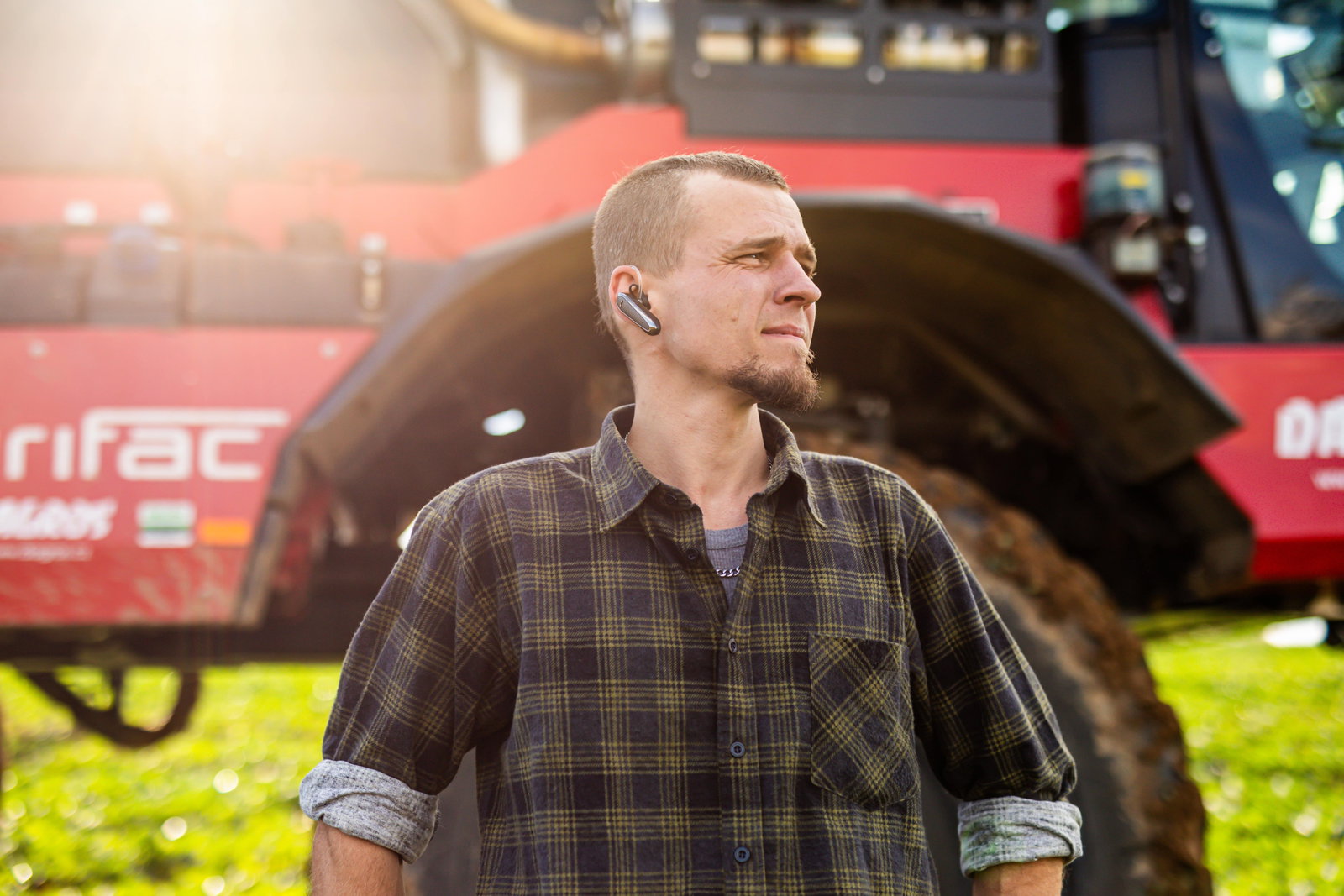 A man stands confidently in front of a large Agrifac sprayer, showcasing his connection to agricultural machinery.