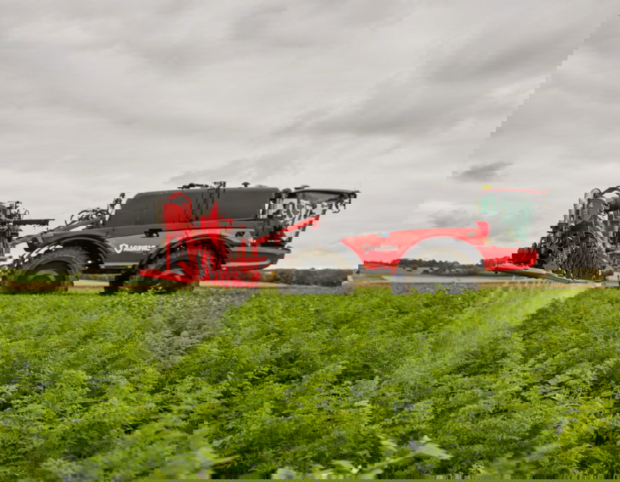 Side view of the machine with the J-boom spraying crops.