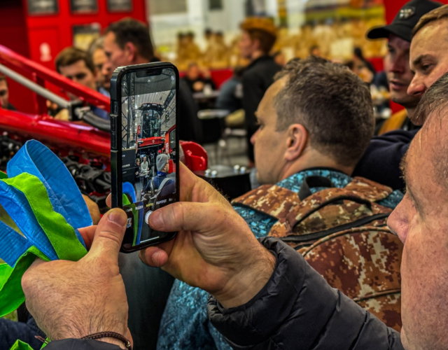 Person taking a photo of a sprayer at an indoor exhibition.