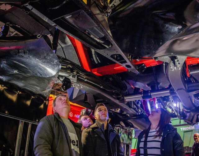 People inspecting the underside of a machine.